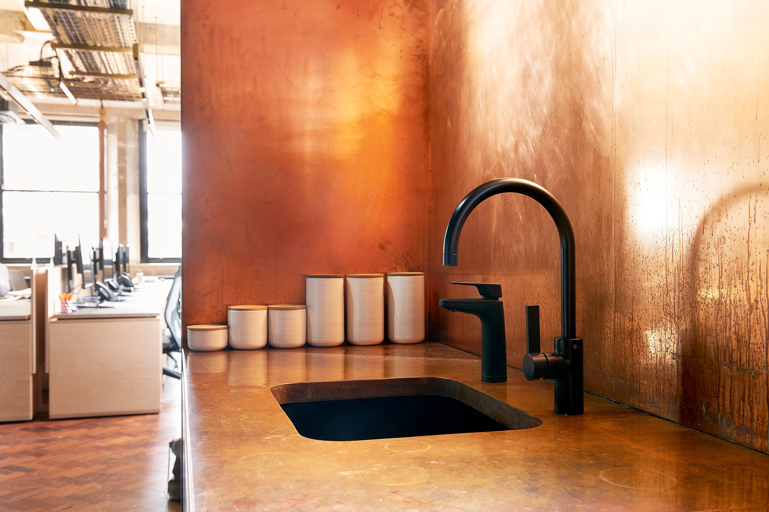 Copper-clad office tea point with a Billi dispenser beside open-plan desks