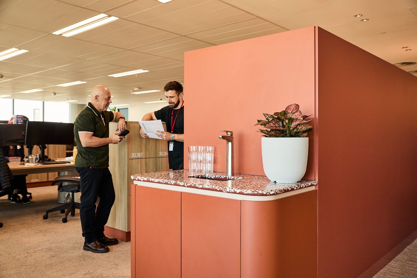 Two colleagues talking beside a Billi water point in an open-plan office