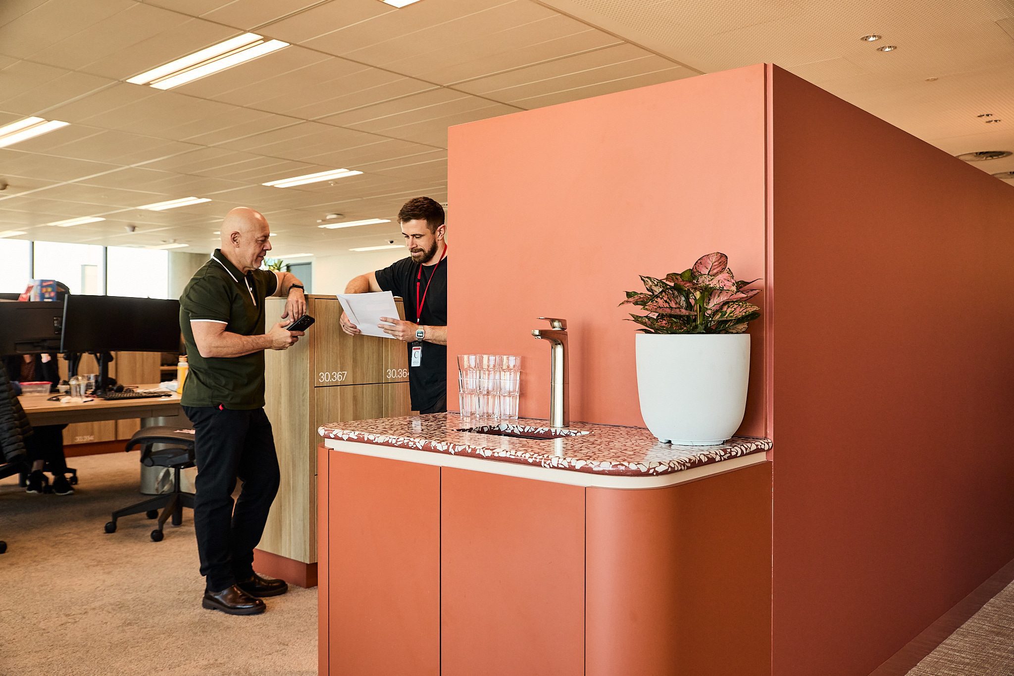 Two colleagues talking beside a Billi water point in an open-plan office